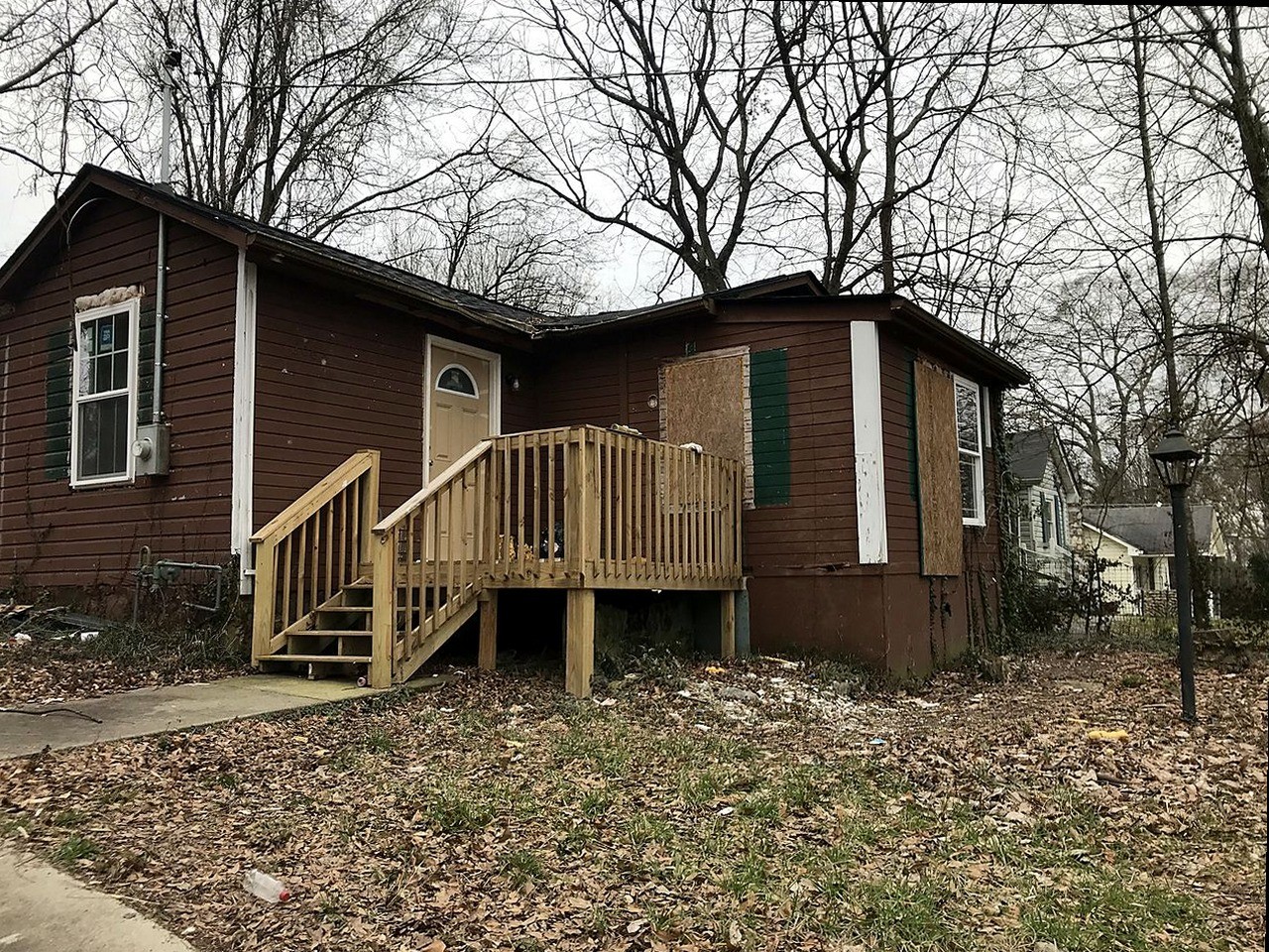 Bungalow before renovation — boarded windows, unfinished deck