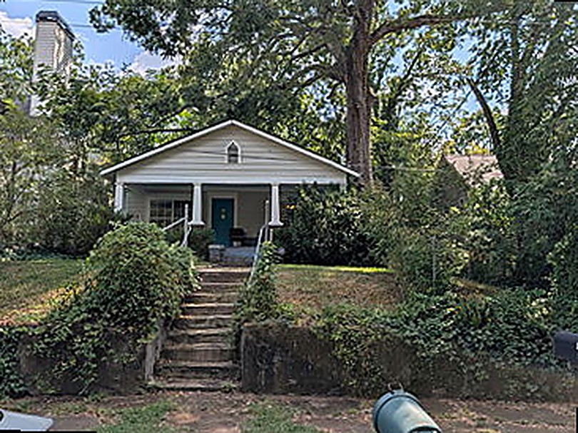 Bungalow before renovation — overgrown frontage, tired porch, hidden from the street