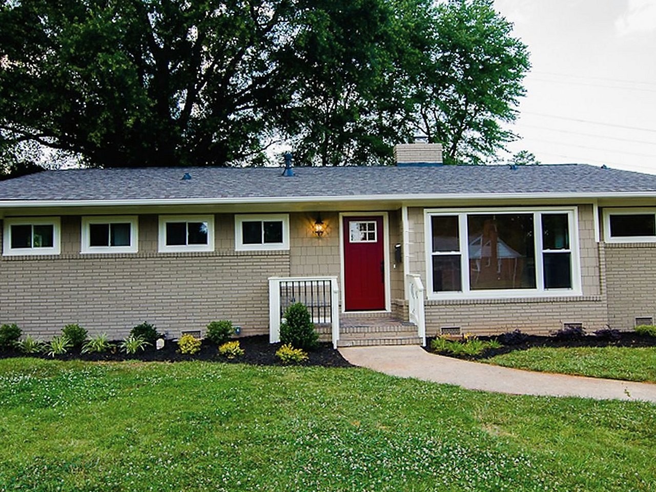 The same brick ranch after renovation — painted exterior, new door, landscaping