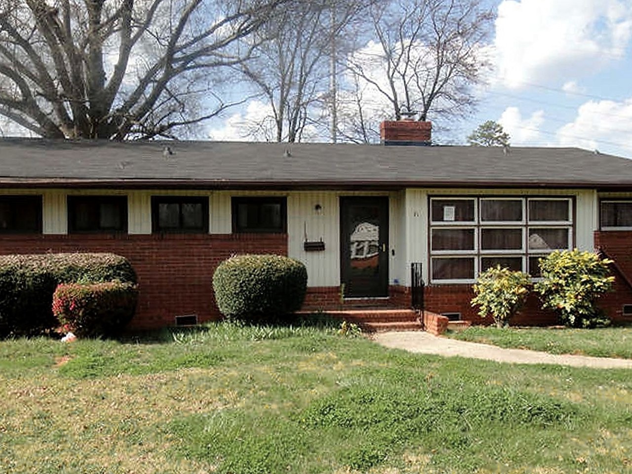 Brick ranch before renovation — overgrown lot, dated exterior