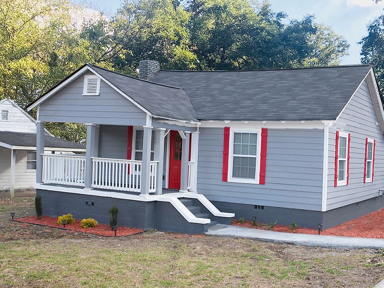 Craftsman bungalow after renovation — grey siding, red door and shutters, new porch rail